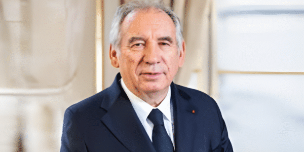 François Bayrou speaking at a political event, wearing a suit and tie.