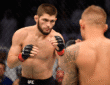Khabib Nurmagomedov standing in the UFC Octagon after a fight, holding the lightweight championship belt.