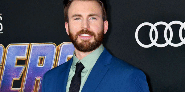 Chris Evans smiling at a red carpet event wearing a black suit