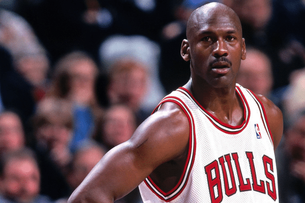 Michael Jordan biography portrait during an NBA game showcasing his iconic jump shot and Air Jordan sneakers